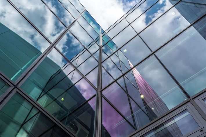 The sky is reflected in the windows of a tall building.